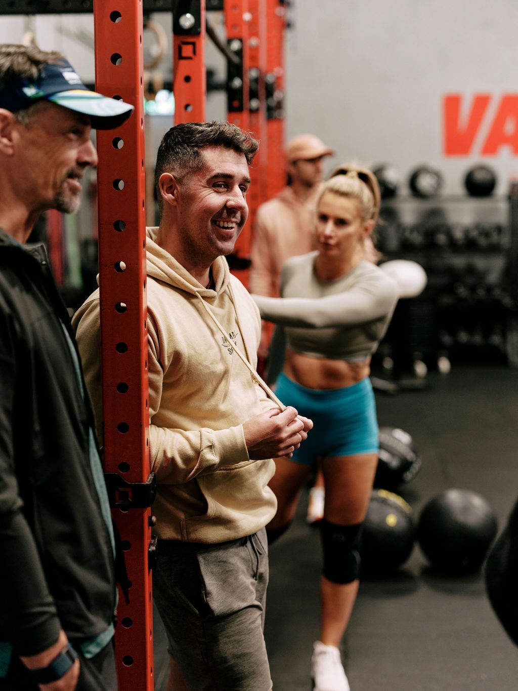 A group of people are standing in a gym talking to each other.