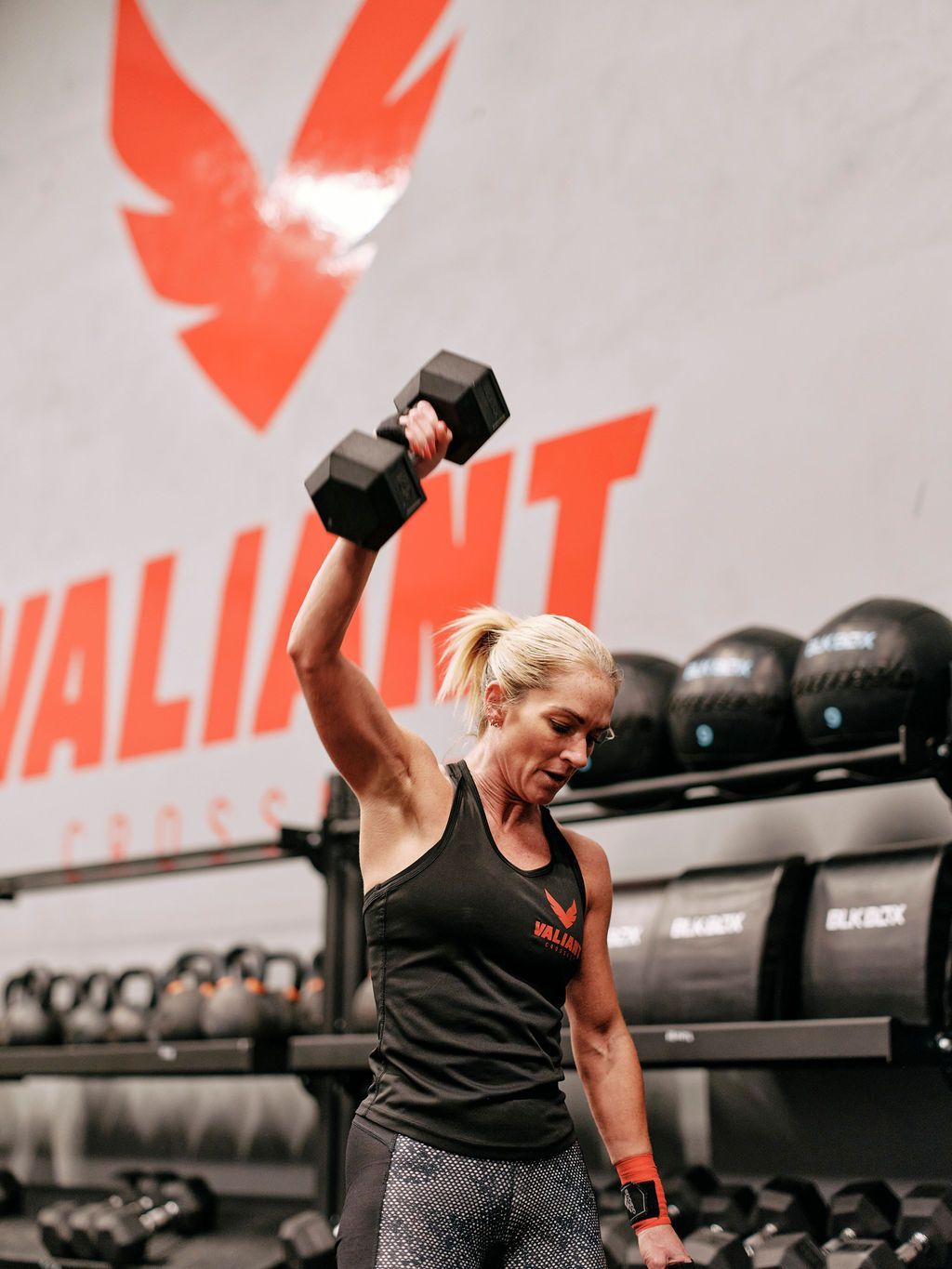A woman is lifting a dumbbell in a gym.