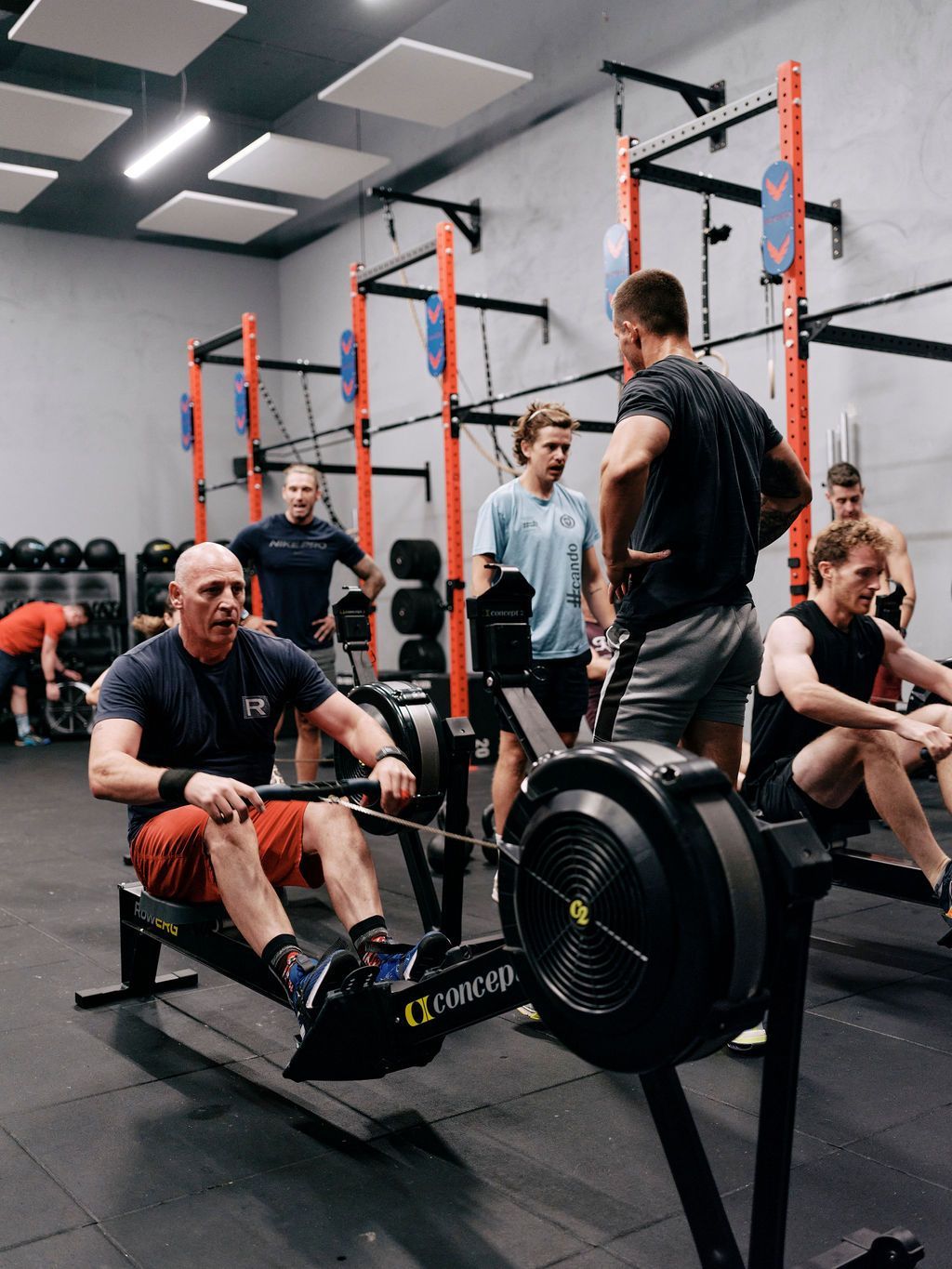 A group of men are using rowing machines in a gym.