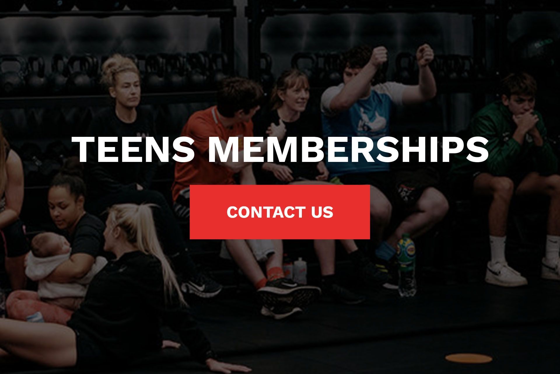 A group of people are sitting on the floor of a gym