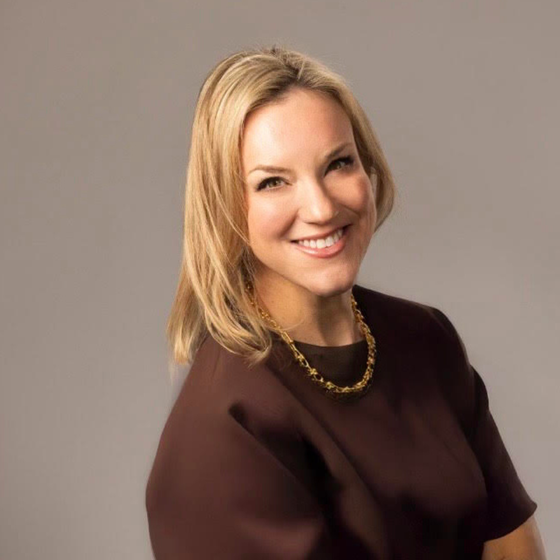 Mary Beth (Owner of MBO Media) wearing brown dress with gold necklace