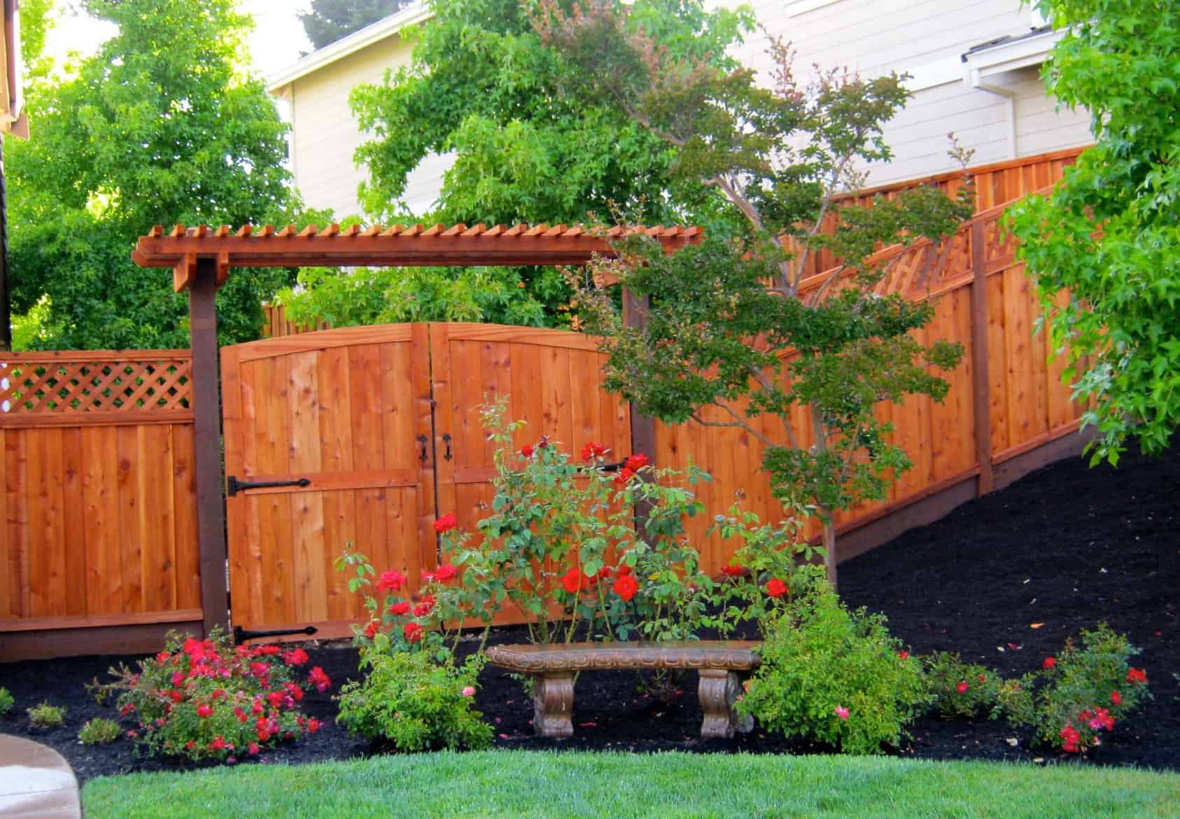 A wooden fence with a bench in front of it