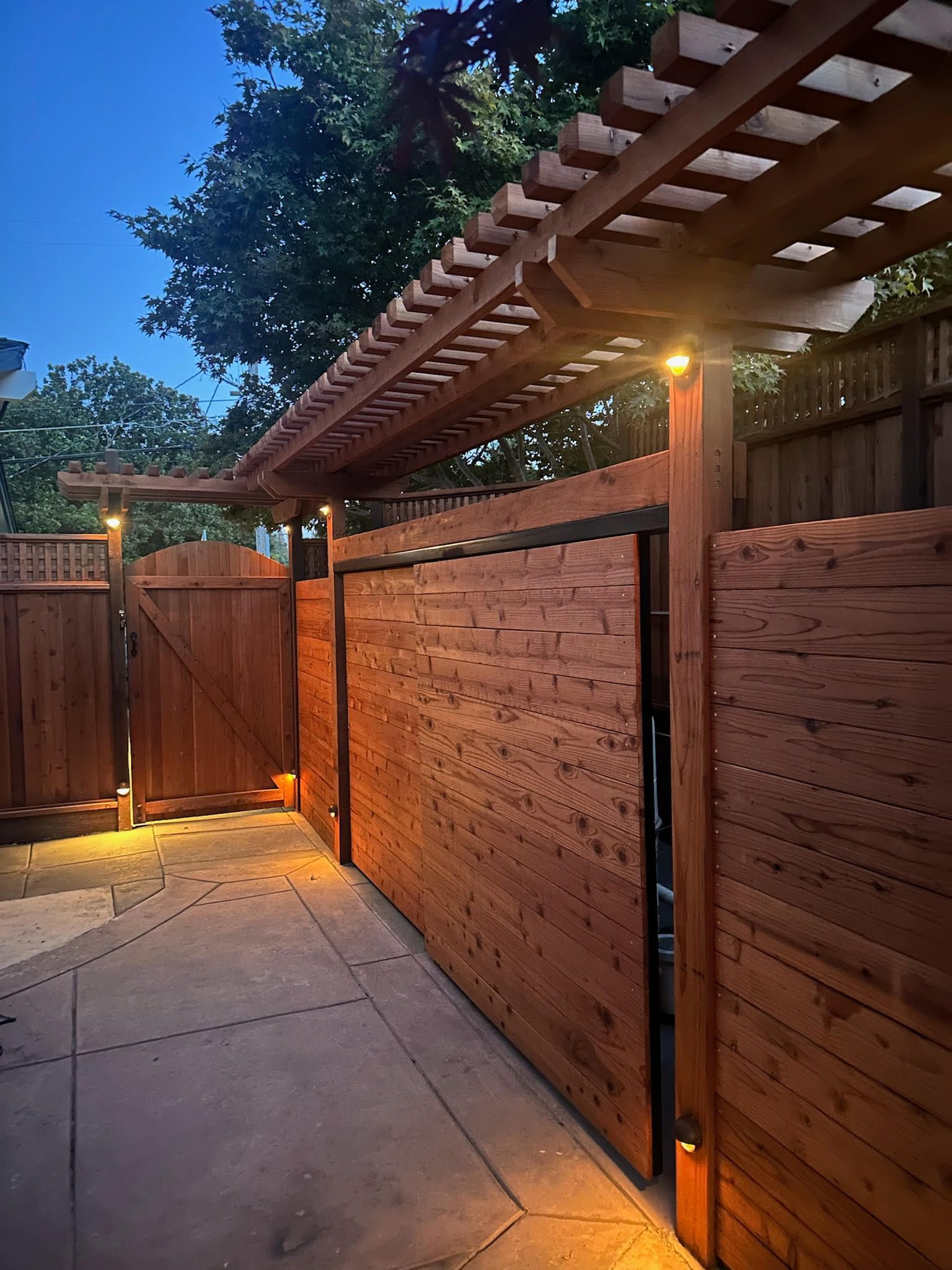 redwood sliding gate with  single gate and trellis at dusk