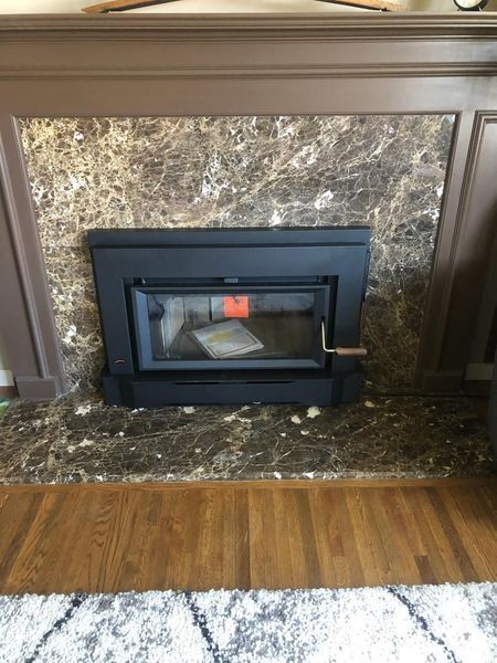 Fireplace with a black insert, marble surround, and wooden mantel.