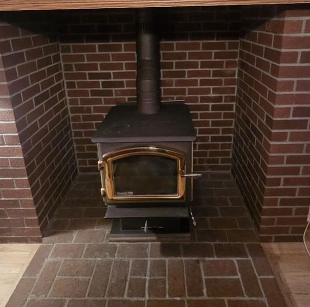 Brick fireplace with a black wood-burning stove inside; brown and tan colors.