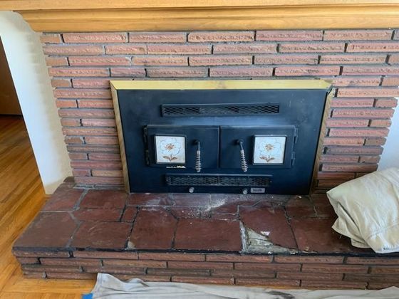 Brick fireplace with a black metal insert and hearth.