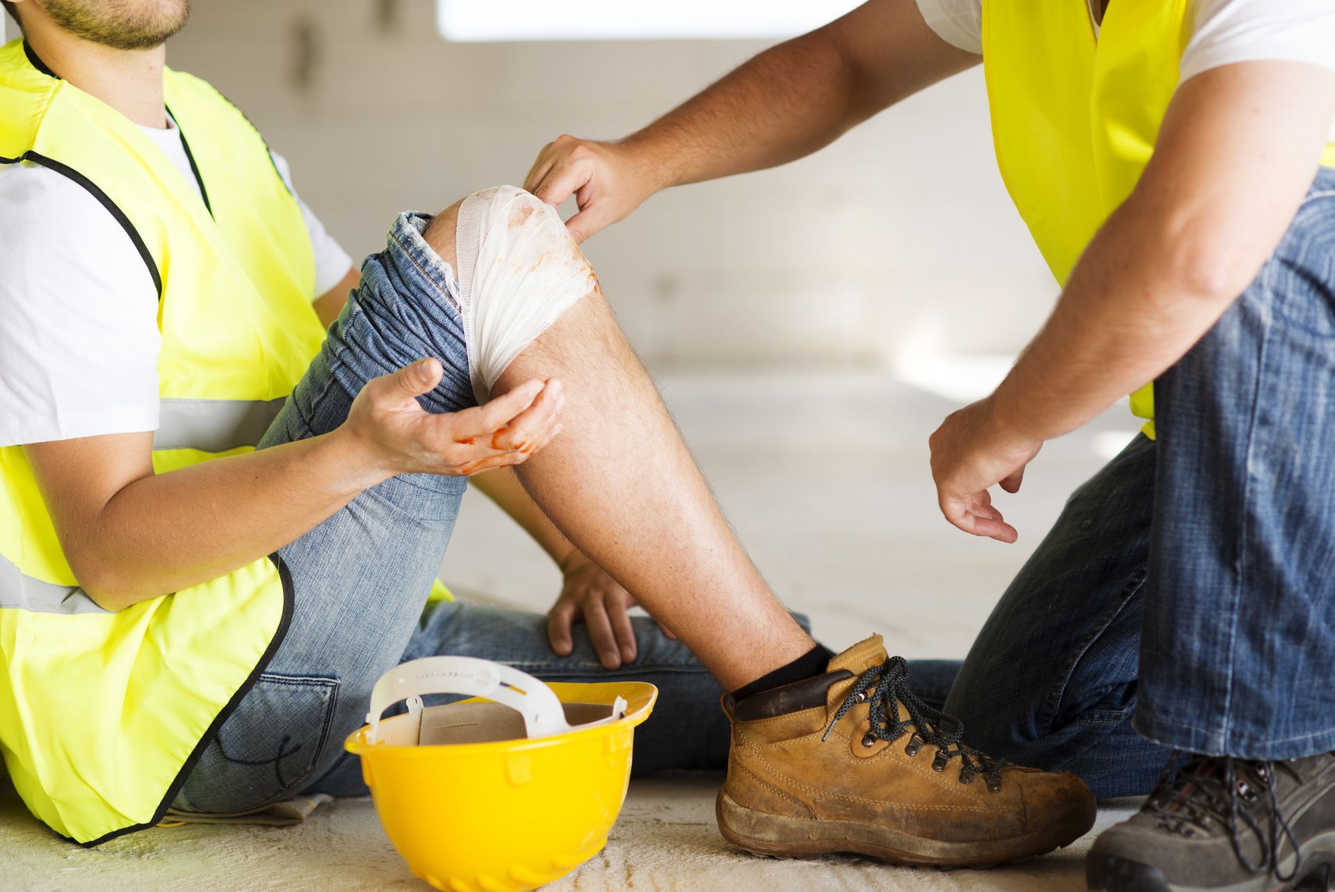 a construction worker is sitting on the floor with a bandage on his knee .
