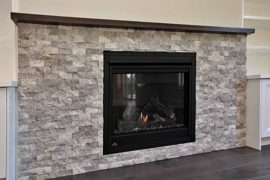 A fireplace is built into a stone wall in a living room.