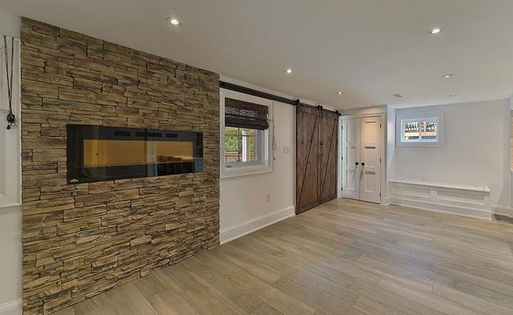 A living room with a stone wall and a fireplace.