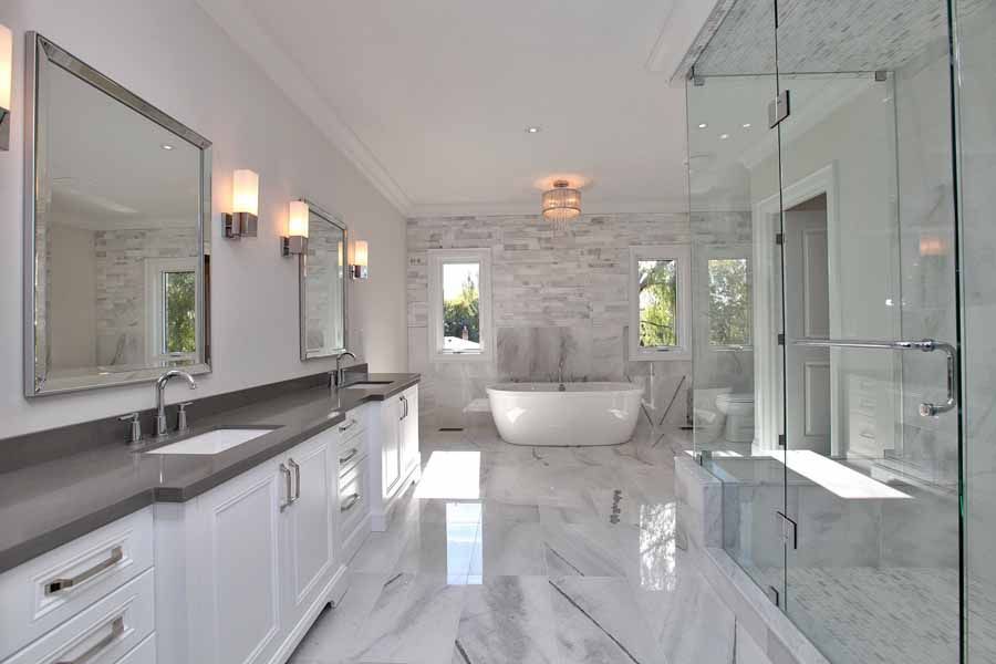 A bathroom with a tub , sinks , mirrors and a walk in shower.