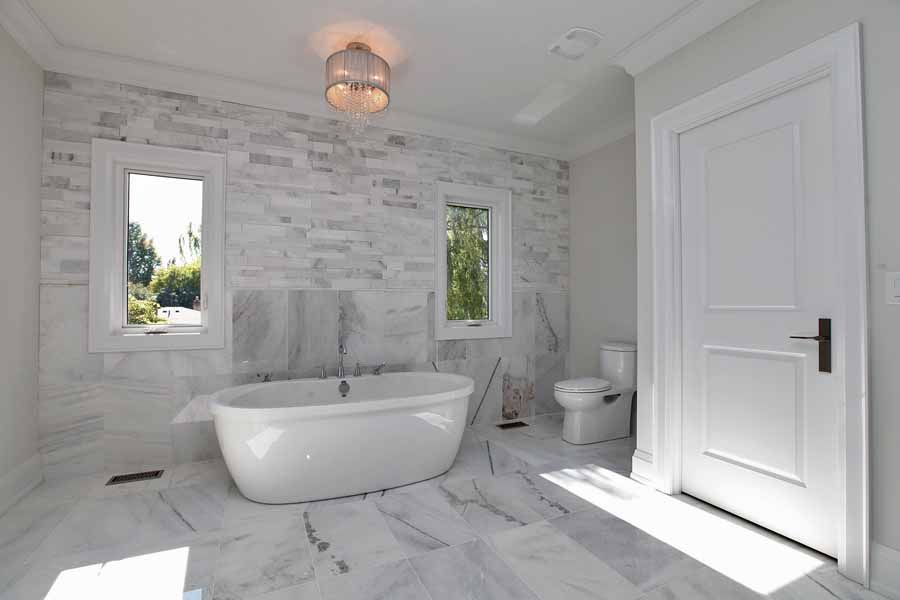 A bathroom with a tub , toilet , and window.