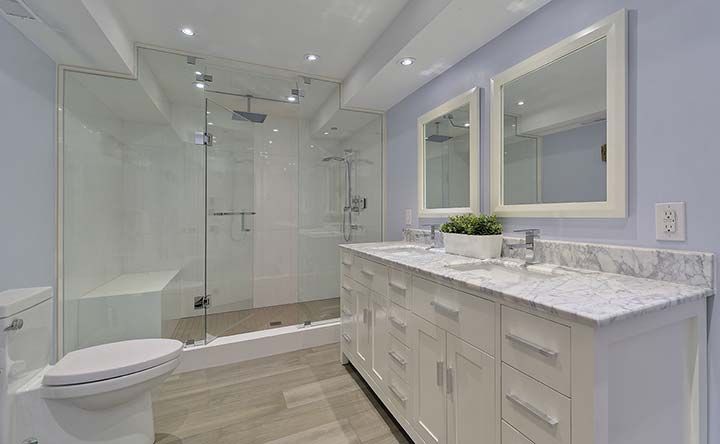 A bathroom with two sinks , a toilet , and a walk in shower.