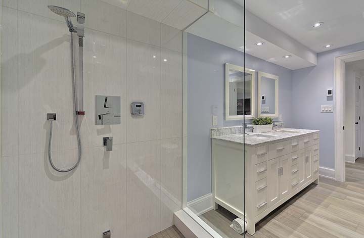 A bathroom with a walk in shower and two sinks.