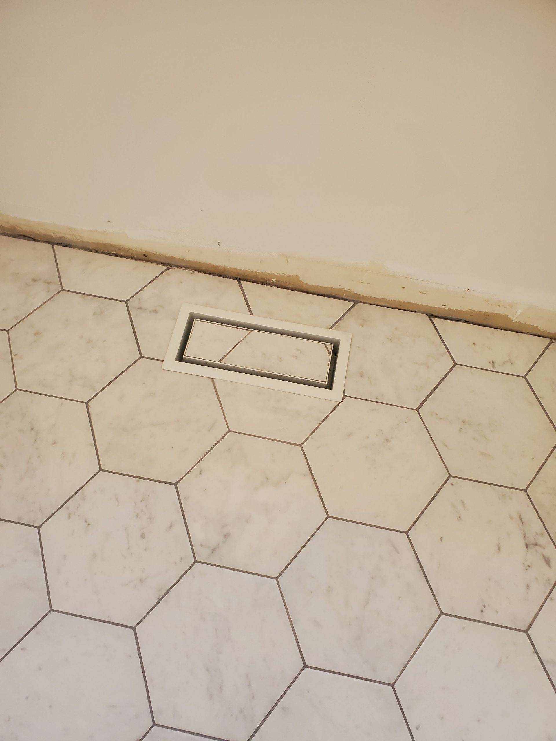 A hexagonal tile floor with a vent in the corner.