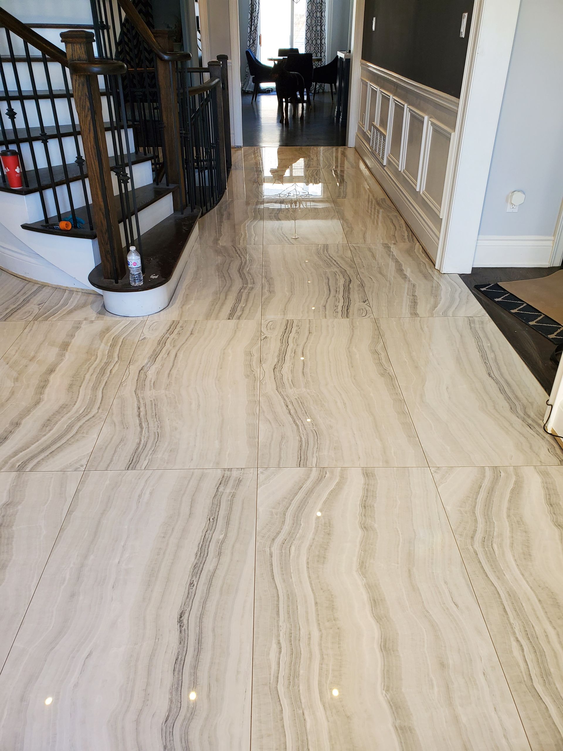 A hallway with a marble floor and stairs in a house.
