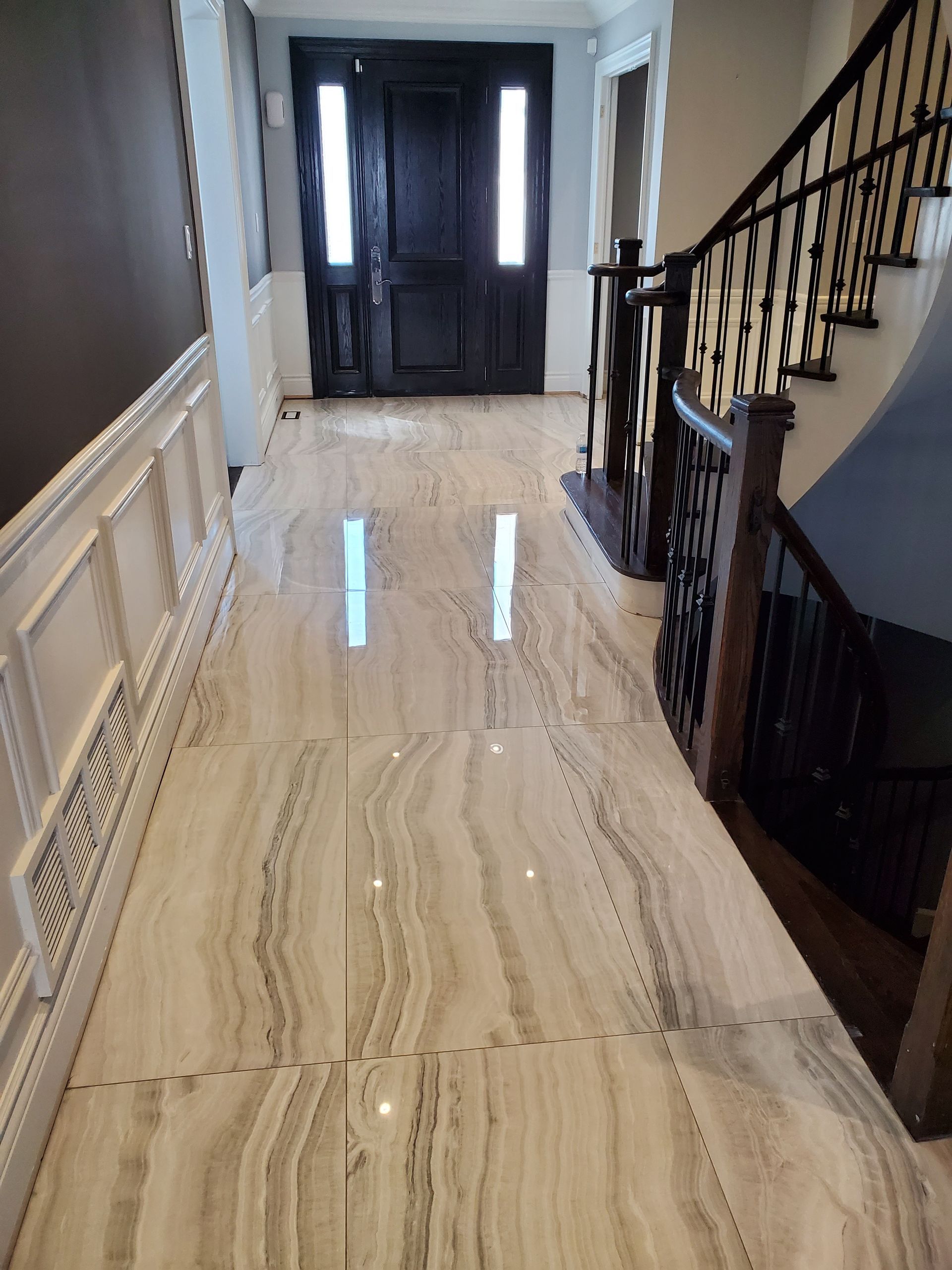 A hallway with a marble floor and stairs in a house.