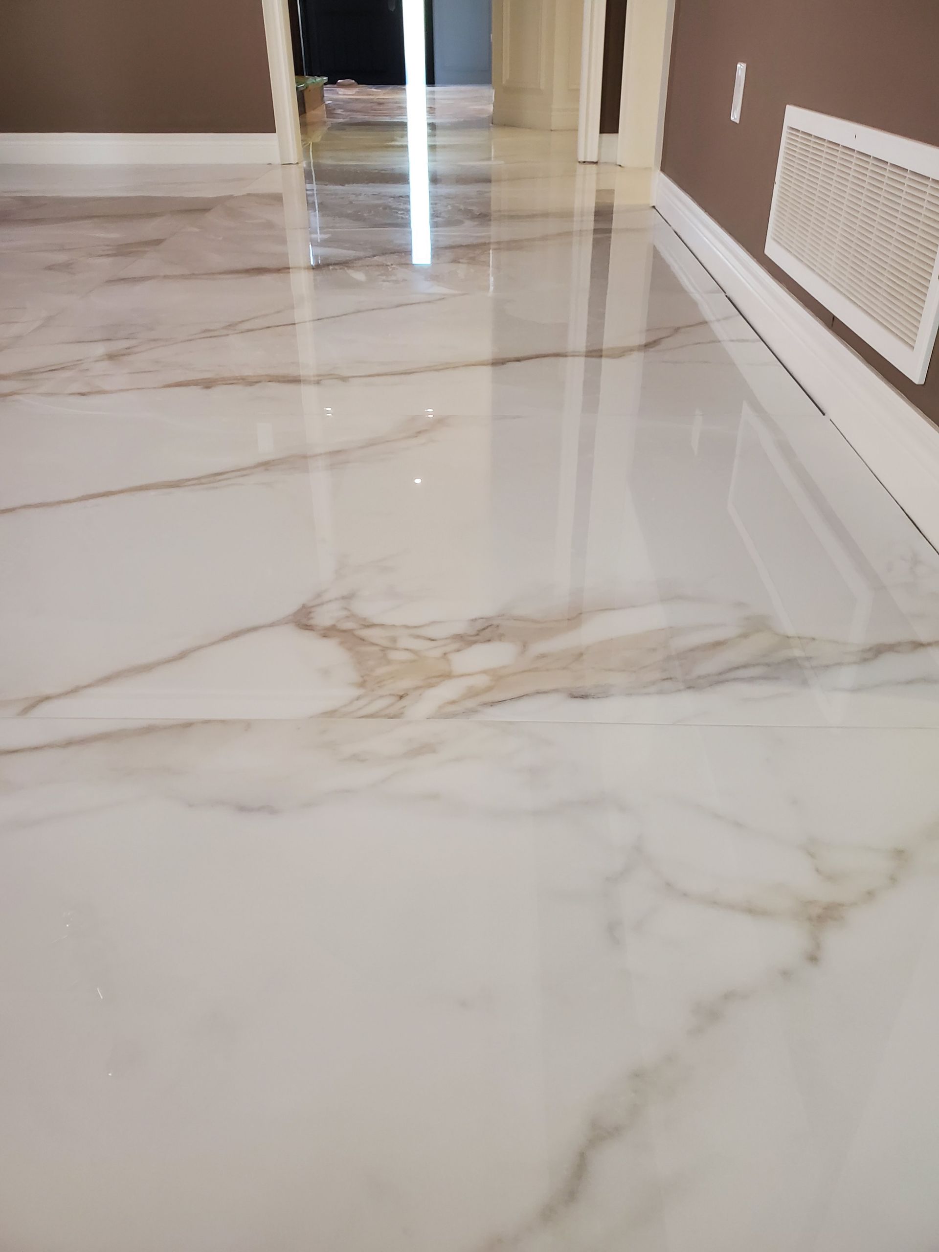 A white marble floor in a room with brown walls.