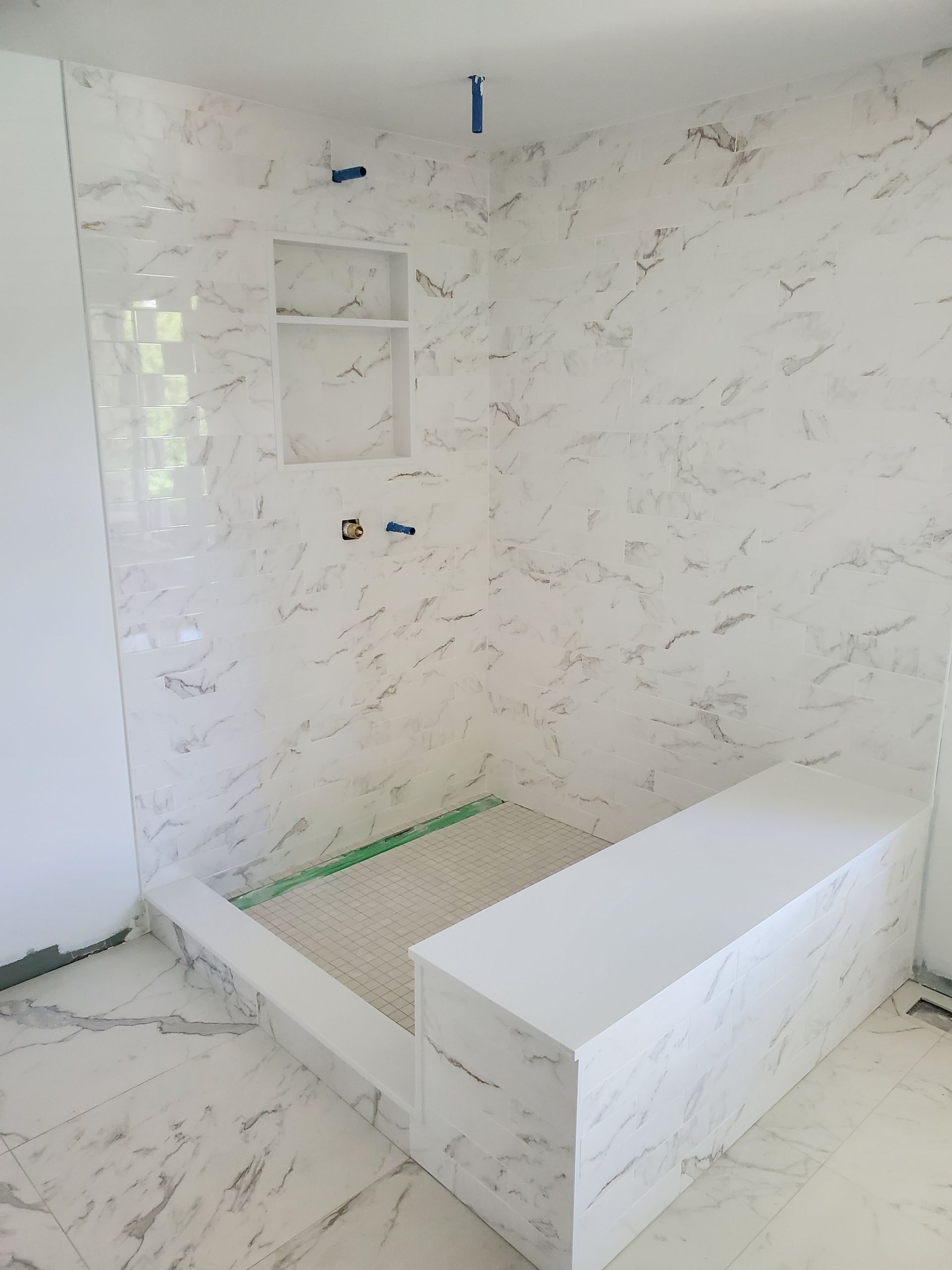 A bathroom with marble tiles and a bathtub.