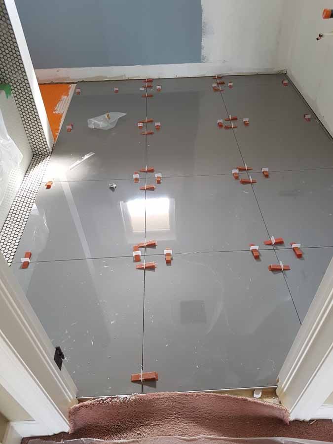 A bathroom floor with tiles being installed and stairs leading up to it.