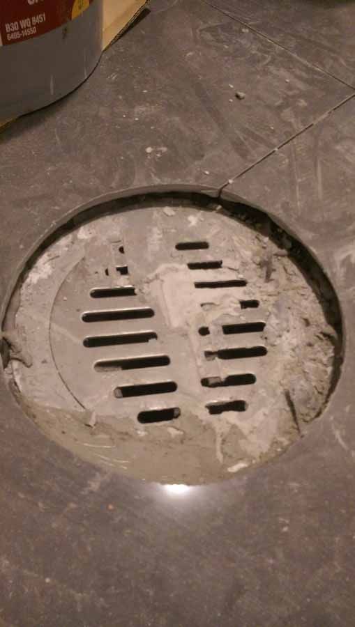 A close up of a manhole cover on a tiled floor.