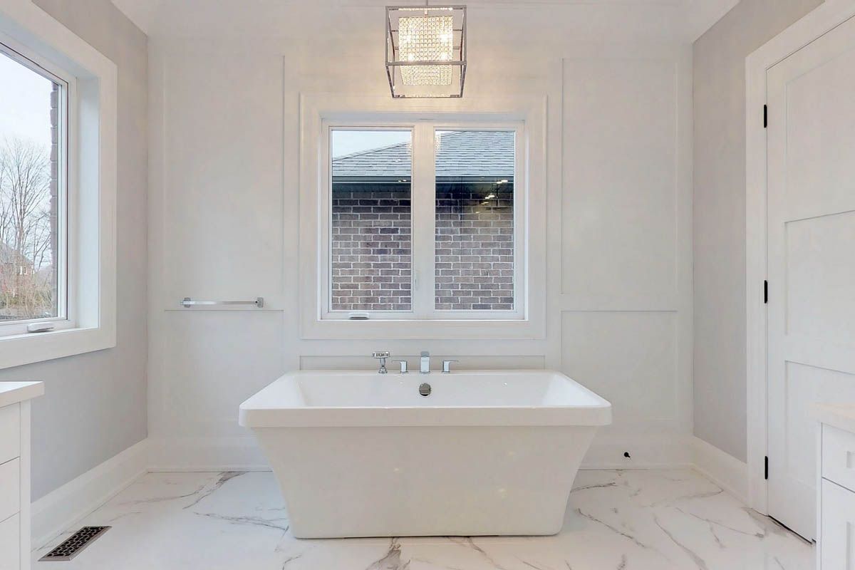 A bathroom with a tub , sink , and window.