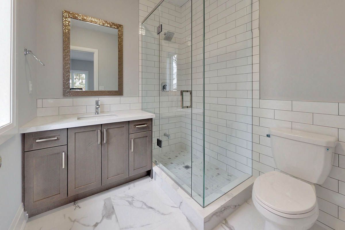 A bathroom with a toilet , sink , shower and mirror.