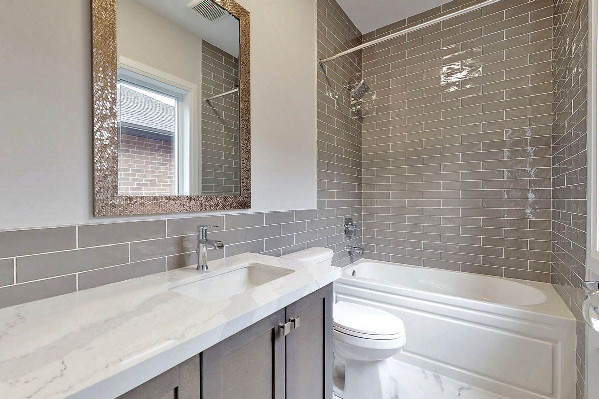 A bathroom with a sink , toilet , tub and mirror.