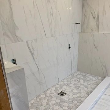 A bathroom with white tiles and a walk in shower.