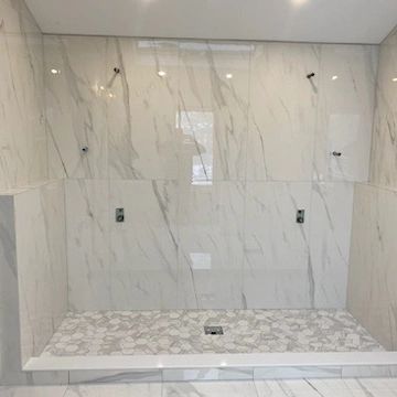 A bathroom with marble tiles and a walk in shower.