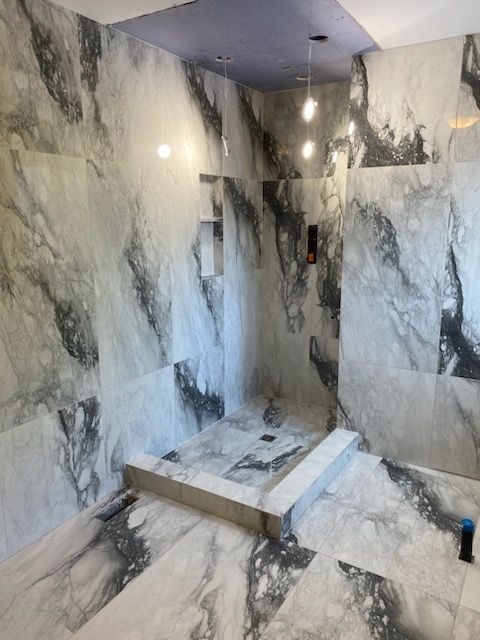 A bathroom with marble tiles and a walk in shower.