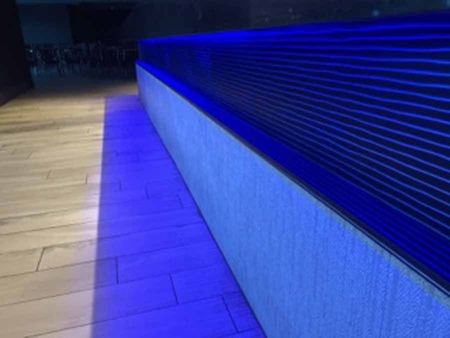 A blue light is shining on a wooden floor.