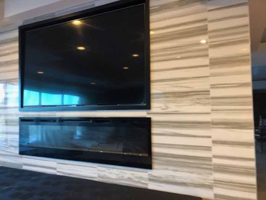 A living room with a fireplace and a flat screen tv on the wall.