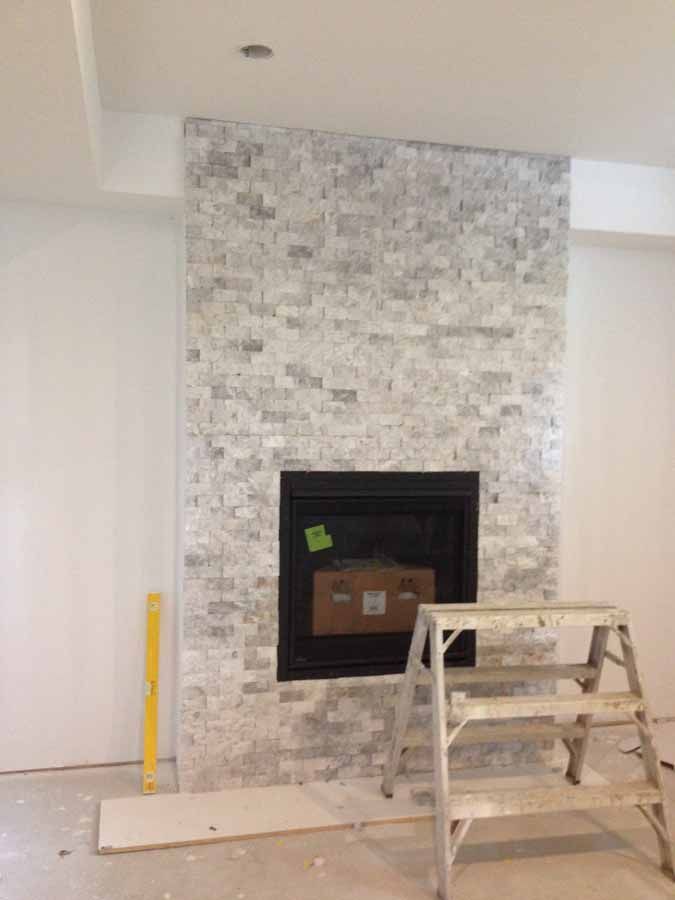 A fireplace is being built in a living room with a ladder next to it.