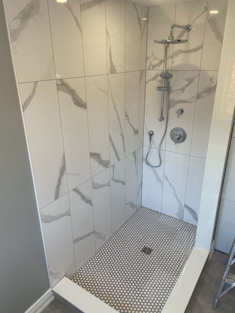 A shower stall with white tiles and a shower head.