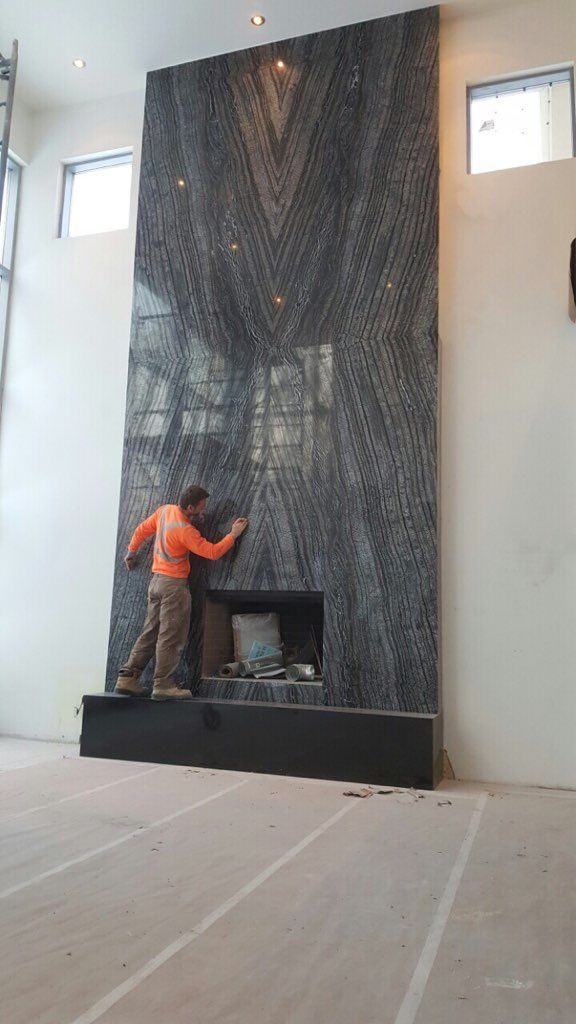 A man is standing in front of a fireplace in a living room.