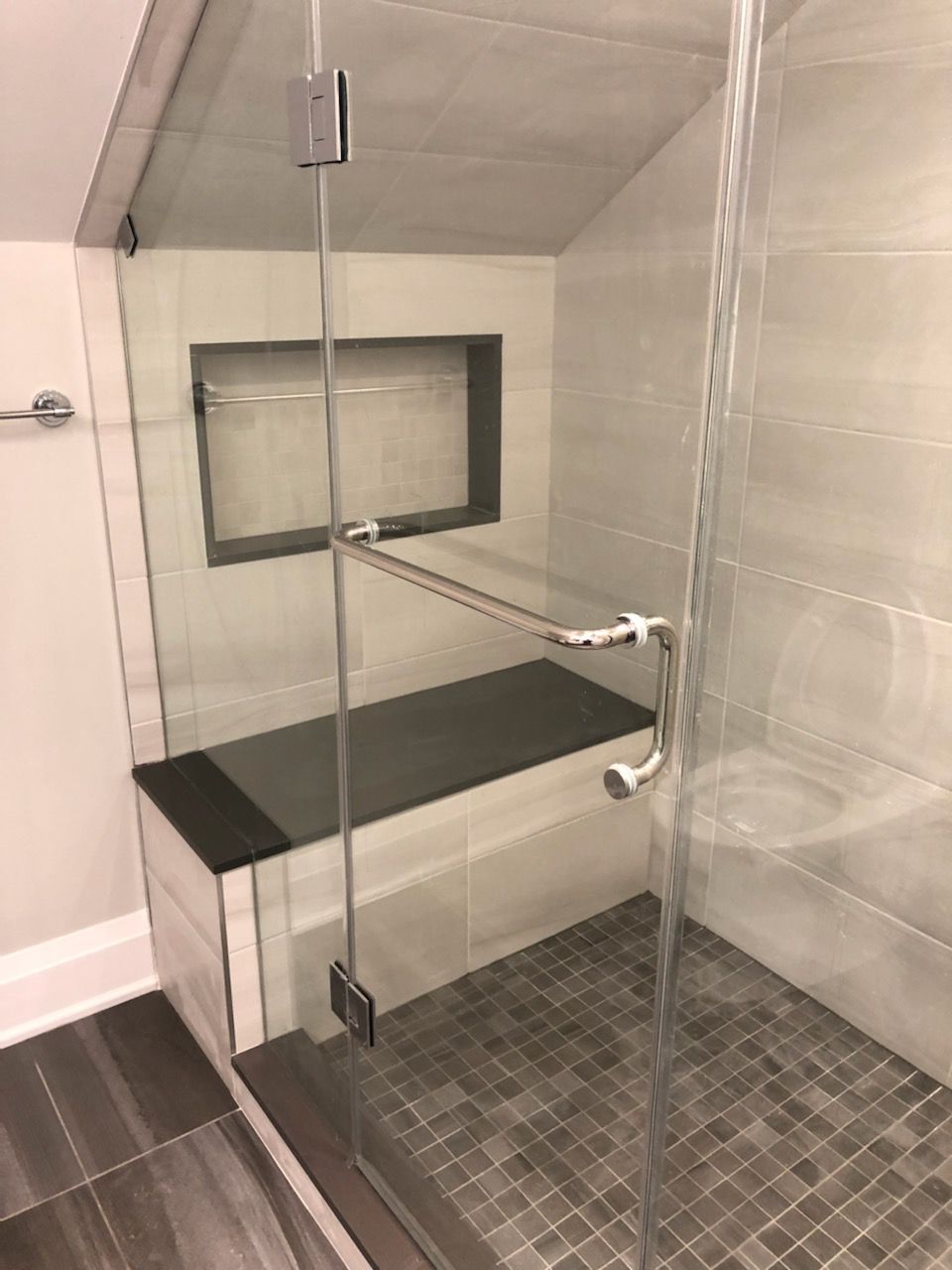 A bathroom with a walk in shower and a bench.