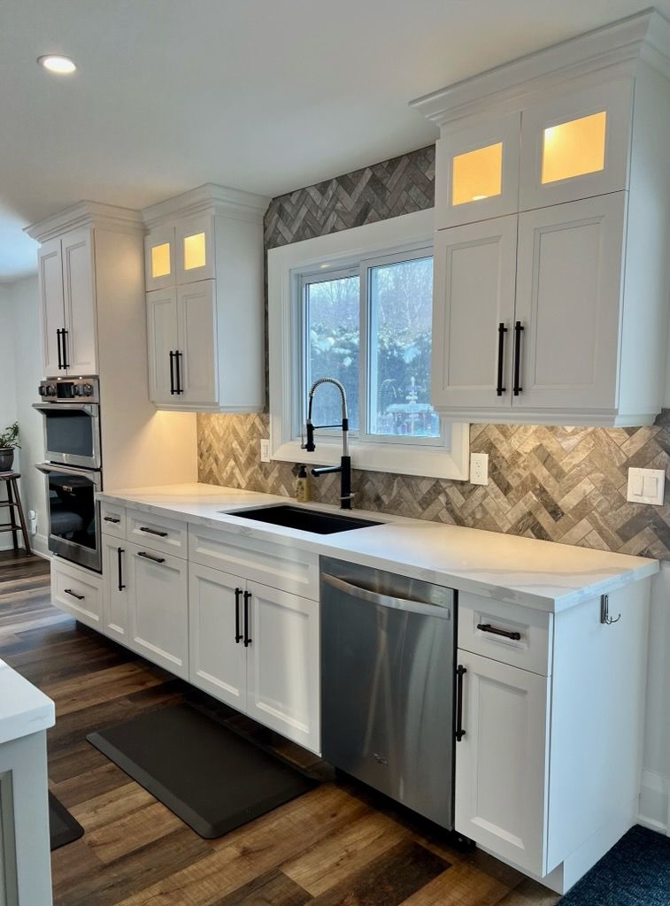 A kitchen with white cabinets , stainless steel appliances , a sink , and a window.