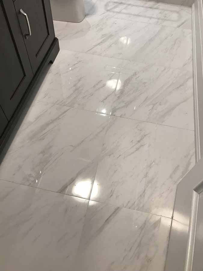 A close up of a white tile floor in a bathroom.