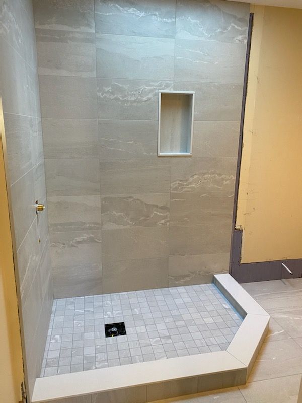 A bathroom with a walk in shower and a tiled wall.