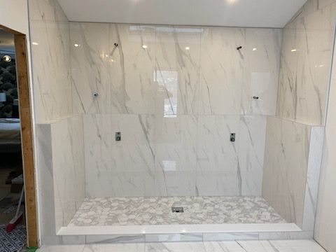 A bathroom with marble tiles and a walk in shower.