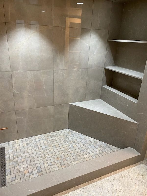 A bathroom with a walk in shower and a bench.