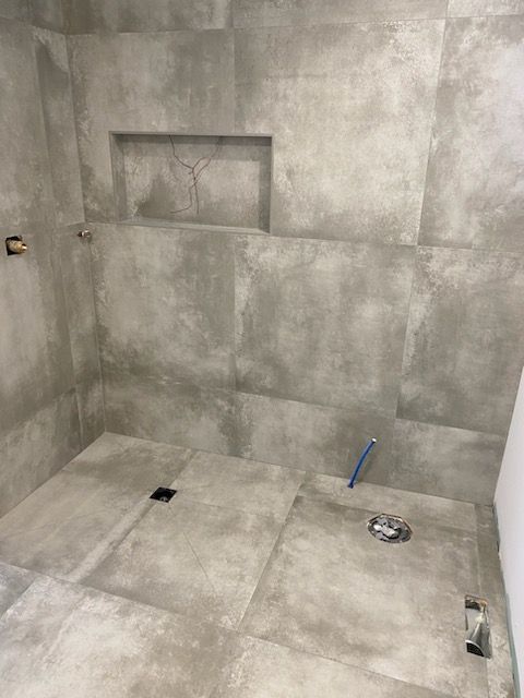 A bathroom with gray tiles on the floor and walls.