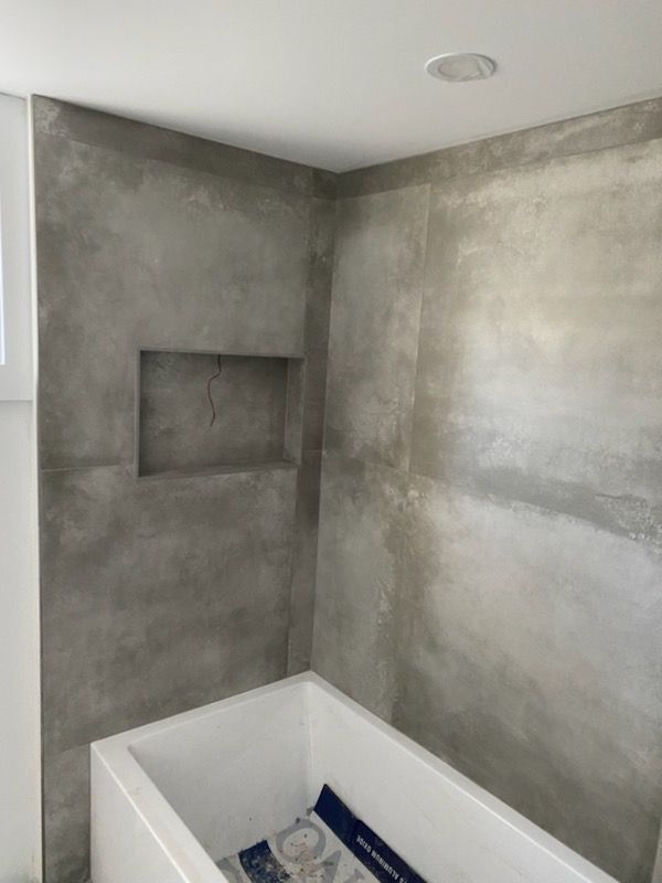 A bathroom with a bathtub and a concrete wall