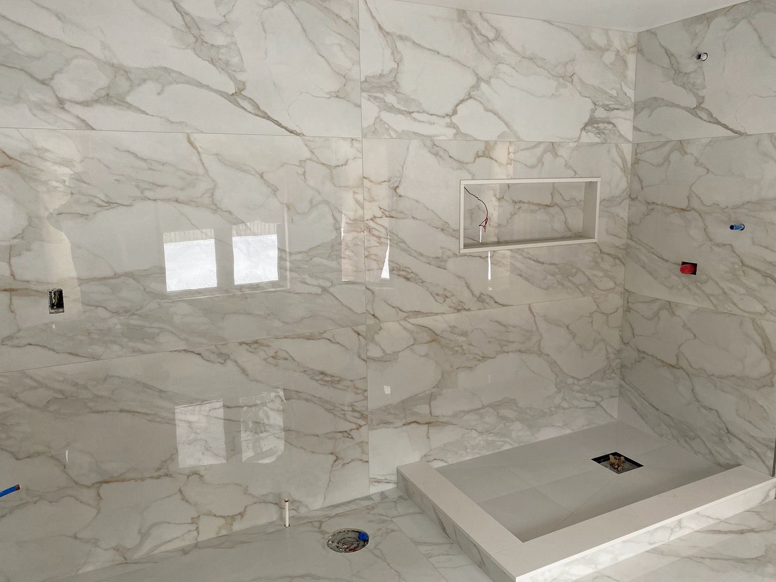 A bathroom with marble tiles and a walk in shower.