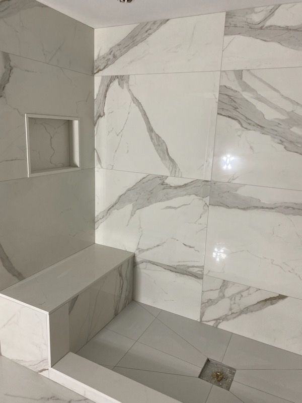 A bathroom with marble tiles on the walls and a bench.