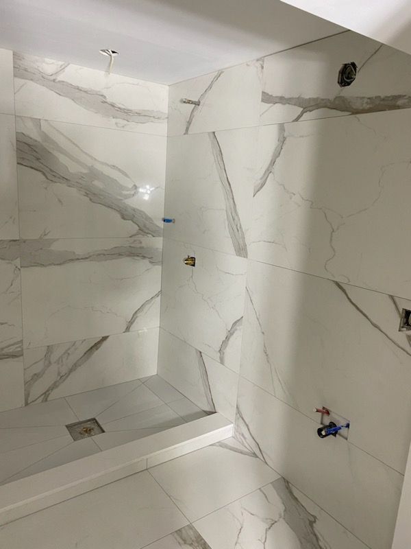 A bathroom with white tiles and a walk in shower.