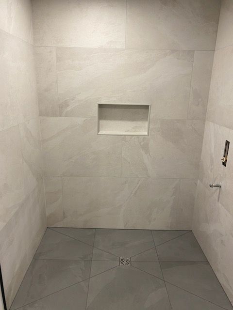 A bathroom with white tiles on the walls and floor.