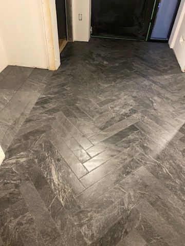 A gray herringbone tile floor in a hallway.