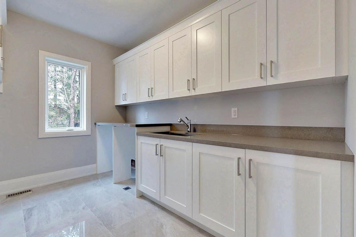 A kitchen with white cabinets , a sink , and a window.