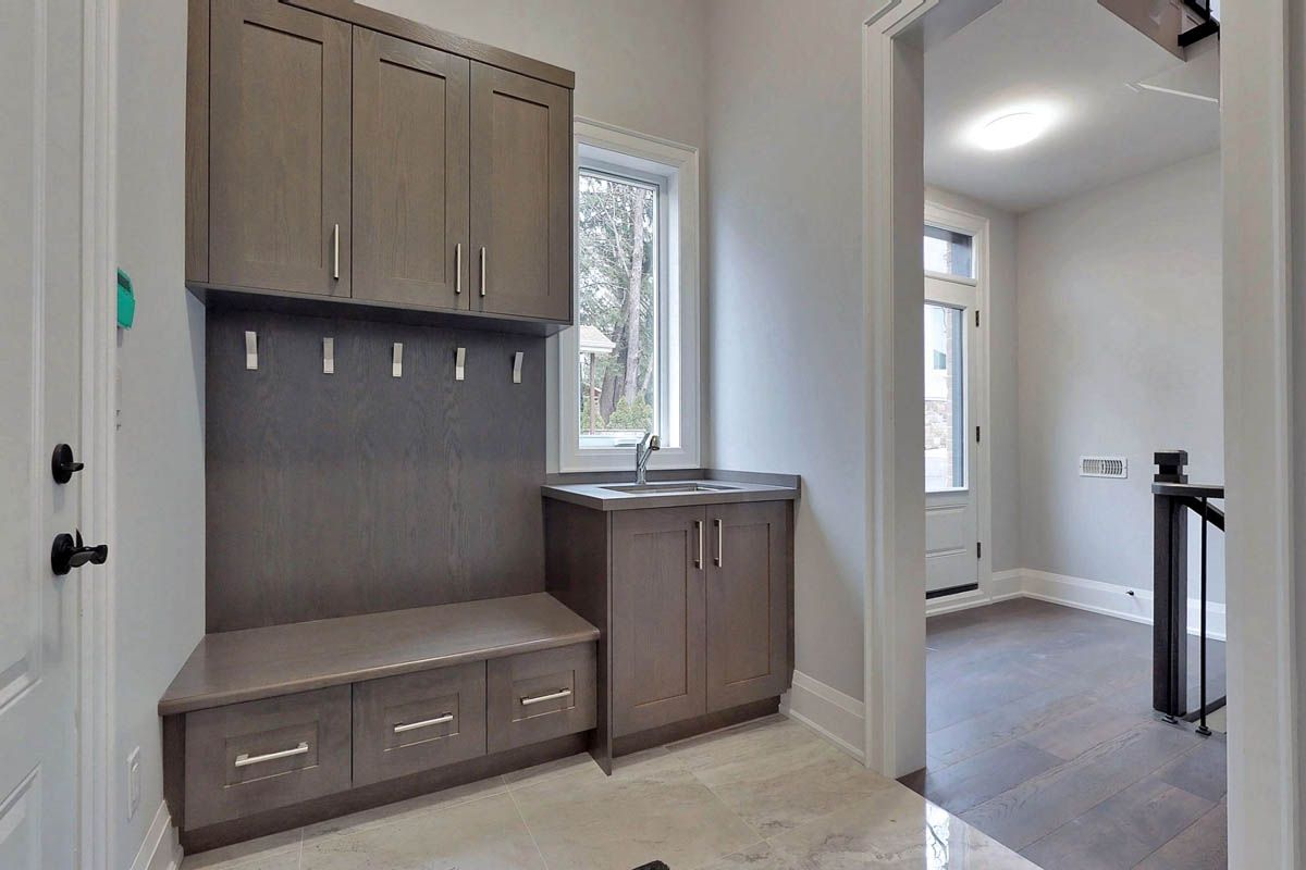 A laundry room with a sink , cabinets and a bench.